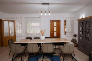 a dining room with a large wooden table and chairs at Casuta de sub deal in Tăuţi