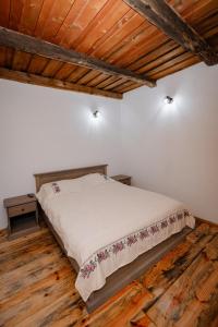 a bedroom with a bed in a room with wooden floors at Casuta de sub deal  +73 photos