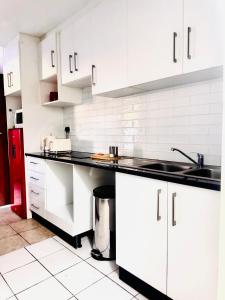a kitchen with white cabinets and black counter tops at Greens Haven, Your Private escape in Cape Town in Cape Town +37 photos