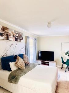 a bedroom with a large white bed and a television at Greens Haven, Your Private escape in Cape Town in Cape Town