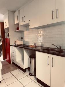 a kitchen with white cabinets and a black counter top at Greens Haven, Your Private escape in Cape Town in Cape Town