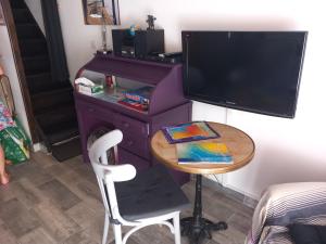 a room with a table and a tv and a small table with a chair at Le CENTAURE Proche Centre Naturiste in Cap d'Agde