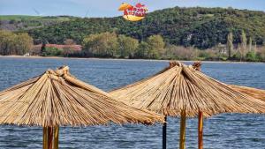 two large straw umbrellas in front of a body of water at Hris-An in Star Dojran +8 photos