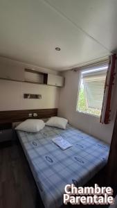 a bedroom with a large bed with a window at Mobil home confort in Hyères