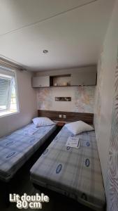 two beds in a small room with a window at Mobil home confort in Hyères