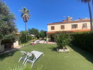 a yard with two white chairs and a house at La casa de bega de mar in Sueca