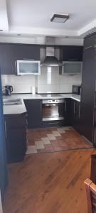 a kitchen with black cabinets and a wooden floor at Apartament Na Wydmie in Ustka
