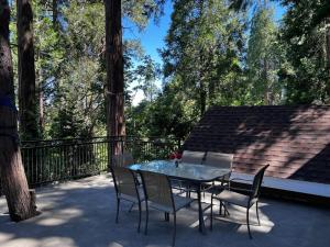 einen Glastisch und Stühle auf einer Terrasse mit Bäumen in der Unterkunft Cozy Cabin in Crestline