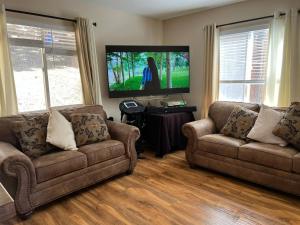 ein Wohnzimmer mit zwei Sofas und einem Flachbildfernseher in der Unterkunft Cozy Cabin in Crestline