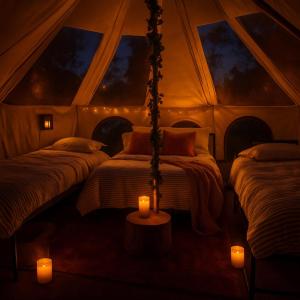 a room with three beds in a tent with candles at Cozy bell tent with heating and smart Tv in Llanfairpwllgwyngyll