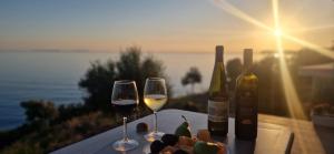 two glasses of wine on a table with a view of the ocean at Oceanfront Oasis in Borsh