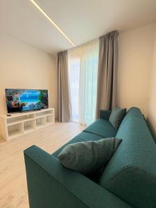 a living room with a blue couch and a flat screen tv at Residence Corallina in Caorle