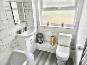 a white bathroom with a toilet and a sink at Swindon Large 3 Bedroom house Parking, Garden in Swindon