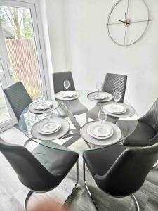 a glass table with chairs and a clock on the wall at Swindon Large 3 Bedroom house Parking, Garden in Swindon +6 photos