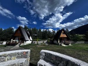 a couple of huts in a field with a stone wall at Zelena dolina Zminica in Zminica