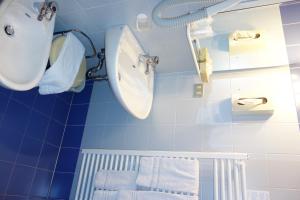 a blue bathroom with a sink and towels at Alpine Touring Hotel-petfriendly in Pozza di Fassa