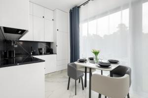 a white kitchen with a table and chairs at Amber Baltic Apartment by Solarento in Niechorze +8 photos