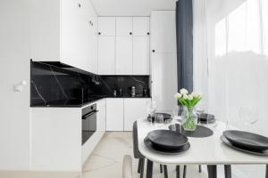 a white kitchen with a white table and black appliances at Amber Baltic Apartment by Solarento in Niechorze