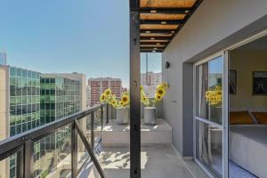 Elle dispose d'un balcon avec deux tournesols en vases. dans l'établissement Fliphaus Mansion Mitre 'A' - 4 pax Duplex Gym & Jacuzzi, à Buenos Aires