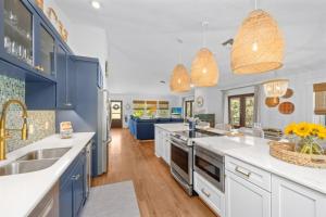 a large kitchen with blue cabinets and white counter tops at Sunkissed Cottage home in Captiva