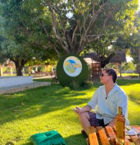 a man sitting on a bench in the grass at Chalé sítio Cumbe in Aracati