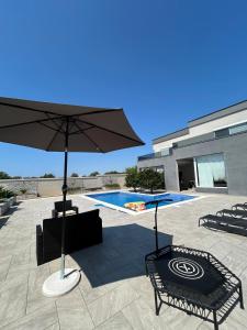 a patio with an umbrella next to a swimming pool at Apartment with pool, accessible for people with disabilities, near Zadar in Bibinje