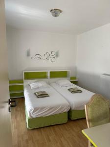 una camera con due letti con lenzuola bianche e un tavolo di Hotel Castel Moor a Le Croisic