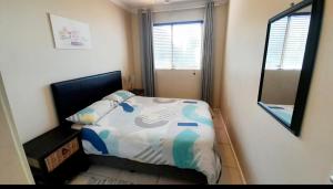 a small bedroom with a bed and a mirror at 84 Camarque Umdloti beach in Umdloti +9 photos