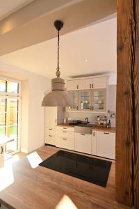 a kitchen with white cabinets and a pendant light at Ferienwohnung Lämmche, EG mit eingezäuntem Garten in Polling +40 photos