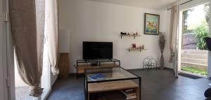 a living room with a tv and a glass table at Les Baraquettes de St clair in Sète