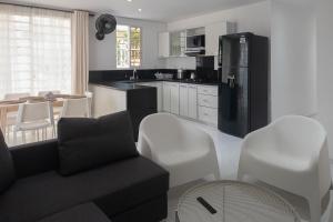 a kitchen with a black refrigerator and white chairs at edificio Alba in Cartagena de Indias