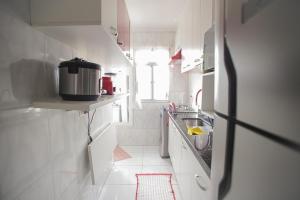a small white kitchen with a sink and a refrigerator at Apt Confortável Cent de SP Luz Brás e Bom Retiro in Sao Paulo