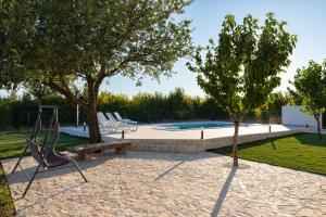 a pool with a bench and trees and a swing at Kuća za odmor Matetić in Unešić
