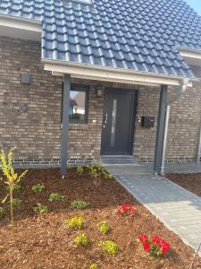una casa con porta d'ingresso e fiori in giardino di Ferienwohnung Verde a Hemmingstedt