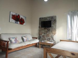 un salon avec un canapé et une télévision au mur dans l'établissement Los Cantaros, à Santa Rosa de Calamuchita