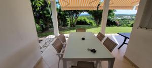 a table and chairs on a porch with a view at Résidence Belle Vue des îles in Sainte-Anne