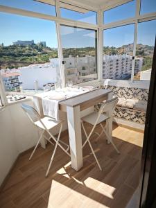 Una mesa y sillas blancas en una habitación con ventanas. en Charmoso T1 Varandas de Malpique, en Albufeira