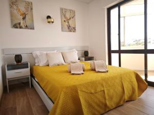 1 dormitorio con 1 cama amarilla y 2 toallas en Charmoso T1 Varandas de Malpique, en Albufeira