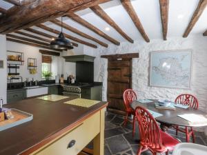 a kitchen with a table and red chairs and a table and a kitchen with at Tyddyn Iolyn in Benllech