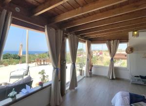 a living room with large windows and a view of the ocean at Esclusiva villa nella natura vista mare e tramonti in Marina di Sorso