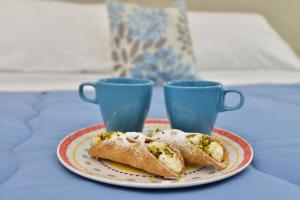 two pastries on a plate with two cups on a table at Appartamento Ortigia Vicolo Lettighieri 22 in Siracusa