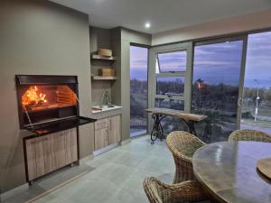 a kitchen with a fireplace and a table with chairs at Casa de Santos - Aloe Villa in Mossel Bay