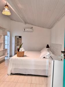 um quarto com uma cama branca e um cesto em Pousada Vila das Águas em Caraíva