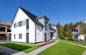 a white house with a black roof at Ferienwohnung Justus in Karlshagen