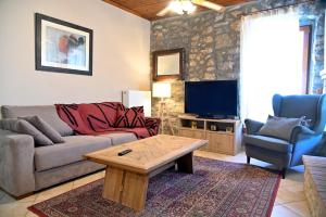 a living room with a couch and a table and a tv at Stone house Amfikleia in Amfikleia