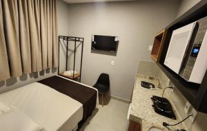 a hotel room with a bed and a desk and a television at FLATS CERRADO santa casa in Montes Claros