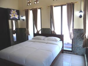 1 dormitorio con 1 cama blanca grande y ventanas en Villa Green House, en Nusa Penida