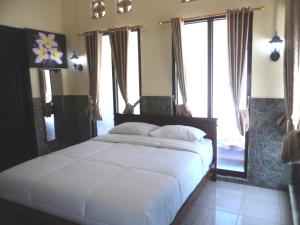 a bedroom with a large white bed with windows at Villa Green House in Nusa Penida