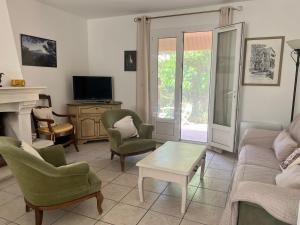 un soggiorno con divano, sedie e TV di Villa Mireille avec jardin et piscine à Lambesc a Lambesc