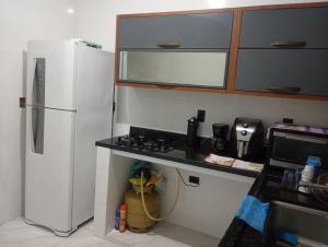 a kitchen with a white refrigerator and a stove at Kitnet temporada in Cabo Frio